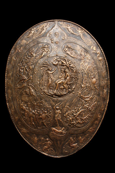photo of bronze reproduction of a shield with intricate relief sculpture set against black background