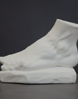 photo of white plaster cast sculpture of left foot on base against gray background