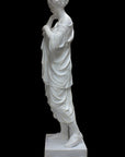 photo of white plaster cast of female figure, namely the goddess Diana, in robes about to clasp two pieces together at proper right shoulder, against black background