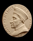 photo of off-white plaster cast relief sculpture of small medallion of male portrait in profile, namely Cosimo de Medici, and text around the edge on black background