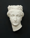 Photo of white plaster cast sculpture of mask/face of female with headband, namely Pauline Bonaparte, on gray background