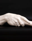 photo of white plaster cast of right hand grasping a staff or pole against black background