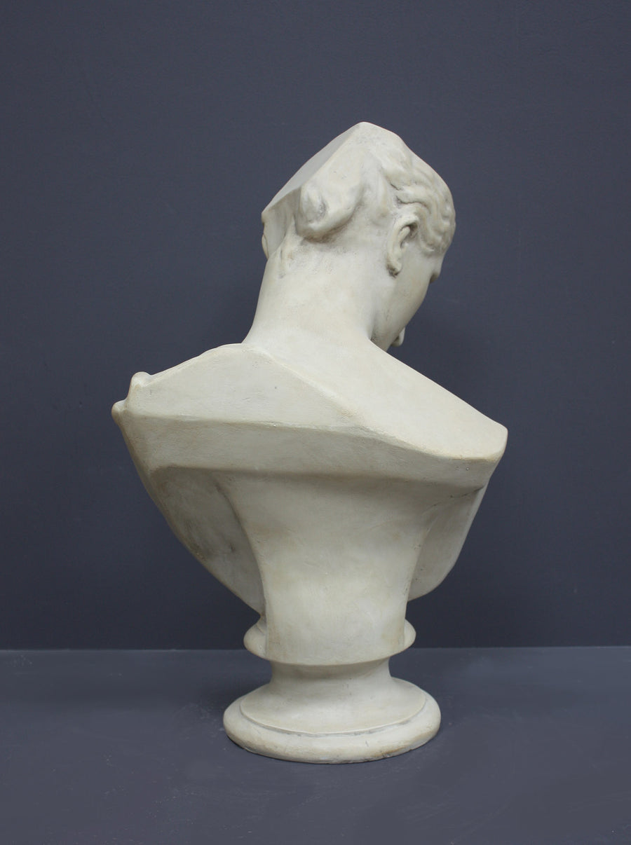 photo of off-white plaster cast sculpture bust of female without top of head and with piece of drapery on socle base on gray background