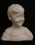 photo of white plaster cast sculpture bust of boy with open mouth, laughing, short hair, and clothes below his shoulders against a black background