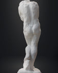 photo of white plaster cast sculpture of nude female figure hugging herself against gray background