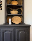 photo of white plaster cast head of male on tall country black cabinet filled with cream and black dishes and bowls