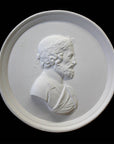 Photo of a white plaster cast of a medallion with a profile of a man wearing a wrath on his head, on a black background, Ariosto