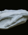 Photo of a white plaster cast of an elderly hand on a black background