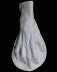 Photo of a white plaster cast of an elderly hand on a black background