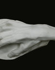 Photo of a white plaster cast of an elderly hand on a black background