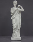 photo of white plaster cast statue of female in robes with left arm raised and holding robe on gray background