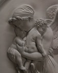 detail photo of plaster cast relief of woman with wings flying with two children nestled against her and an owl flying on a dark background