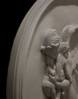 detail photo of plaster cast relief of woman with wings flying with two children nestled against her and an owl flying on a dark background