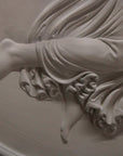 detail photo of plaster cast relief of female with wings flying and a cherub on her back on black background