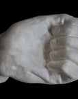 Photo of white plaster cast of a life cast of a clenched fisted hand on a black background