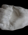 Photo of white plaster cast of a life cast of a clenched fisted hand on a black background