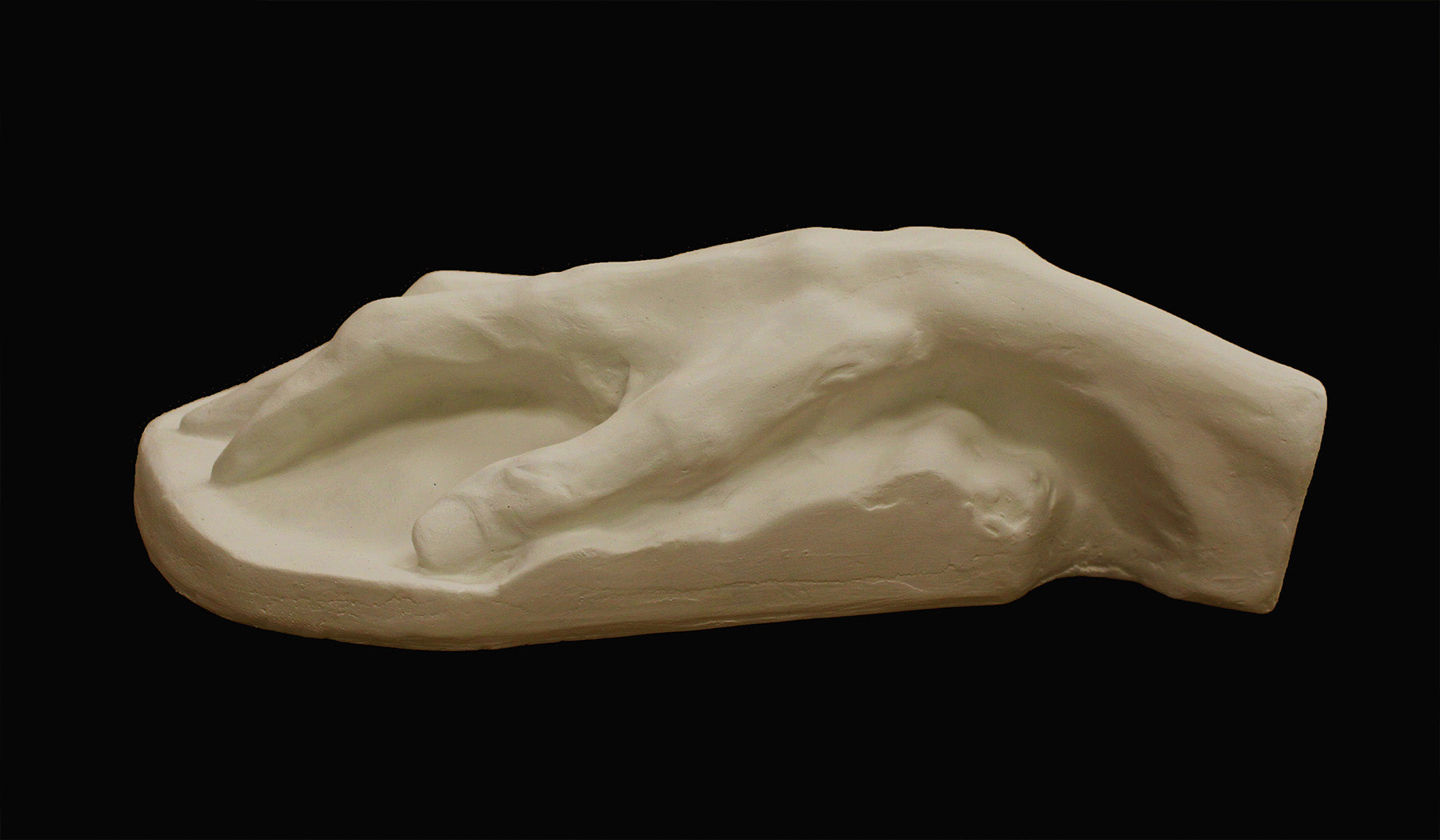 Photo of a white plaster cast of an elderly hand on a black background