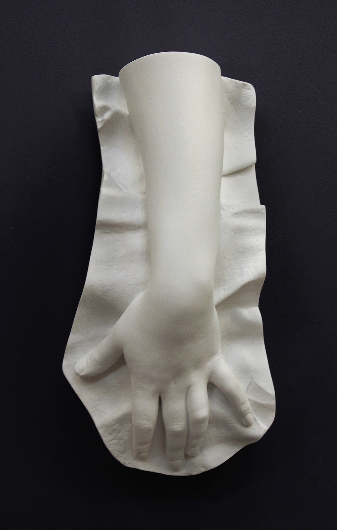 Plaster cast of a female hand on a gray background