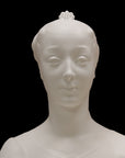 photo of white plaster cast of female bust with up-do and dress against black background