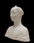 photo of white plaster cast of female bust with up-do and dress against black background