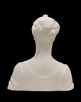 photo of white plaster cast of female bust with up-do and dress against black background