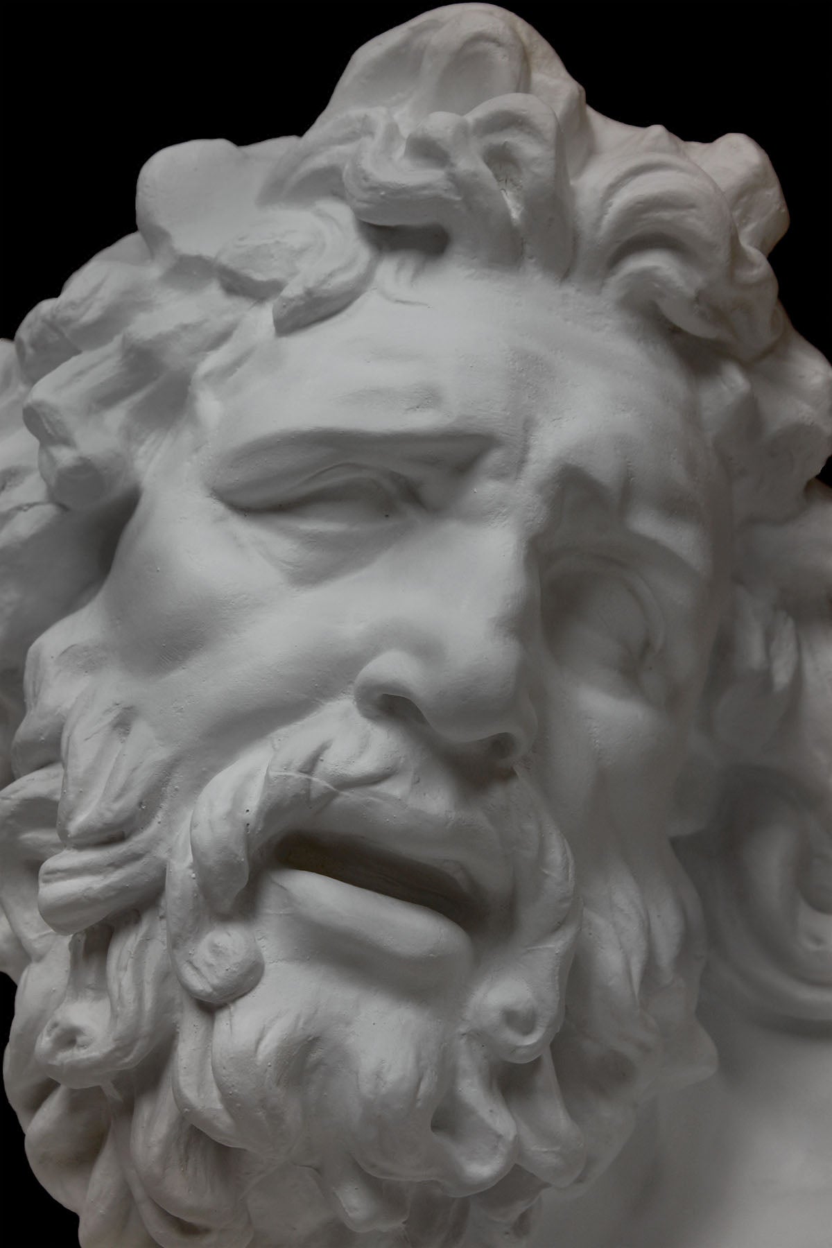 Photo of a detail of a plaster cast of the Laocoon mask on a black background