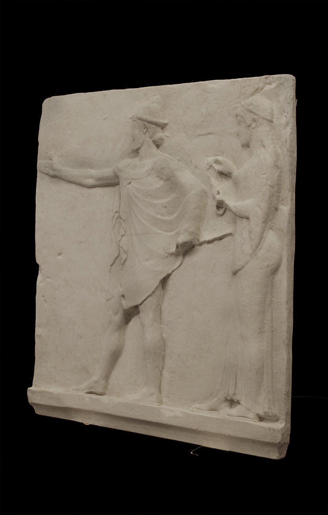 photo of plaster cast sculpture relief of two figures walking to the left, the male reaching out his right hand and the female behind him