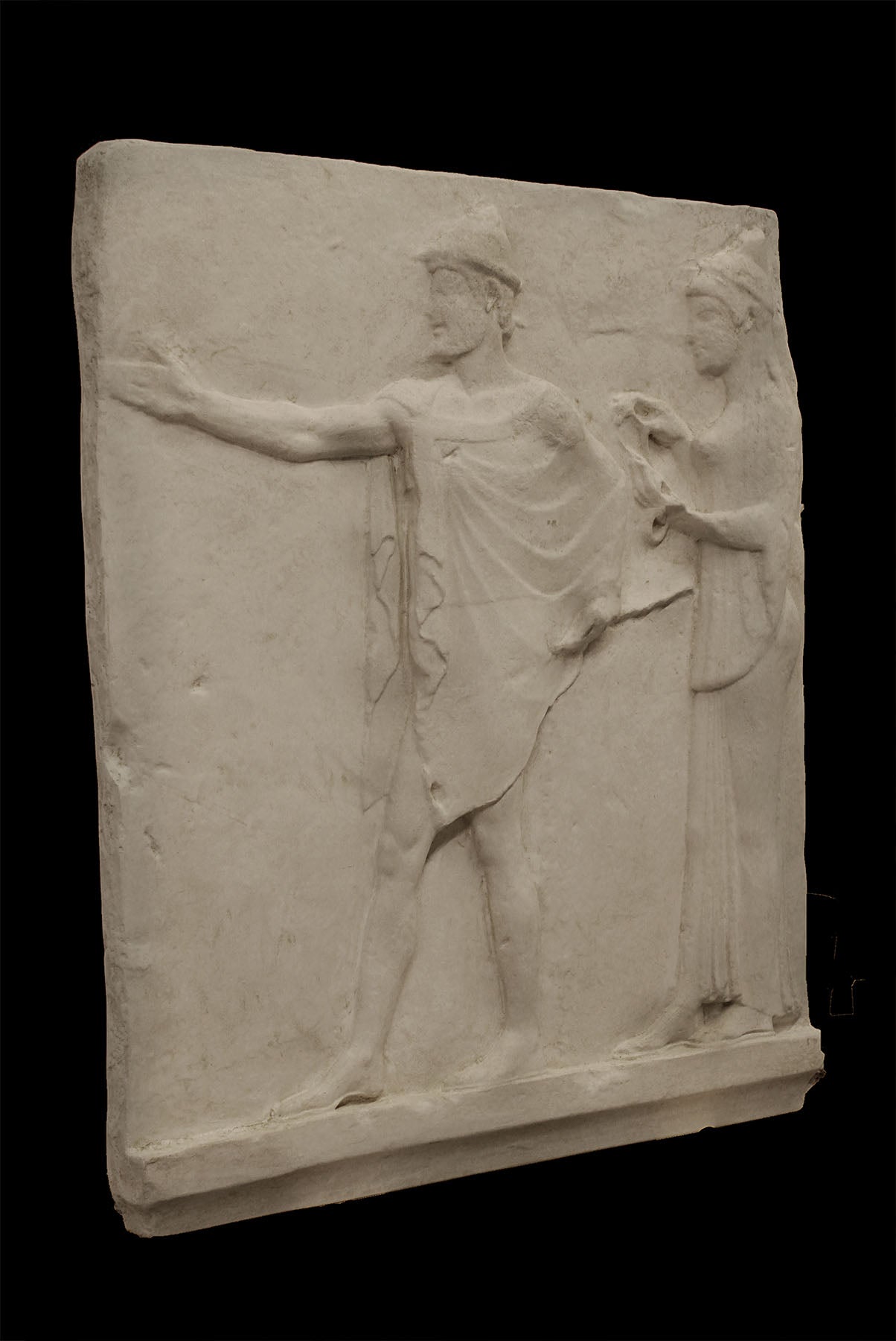 photo of plaster cast sculpture relief of two figures walking to the left, the male reaching out his right hand and the female behind him