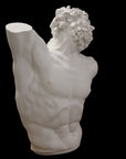 photo with black background of plaster cast of sculpted male torso and head with curly hair and beard, namely Laocoon