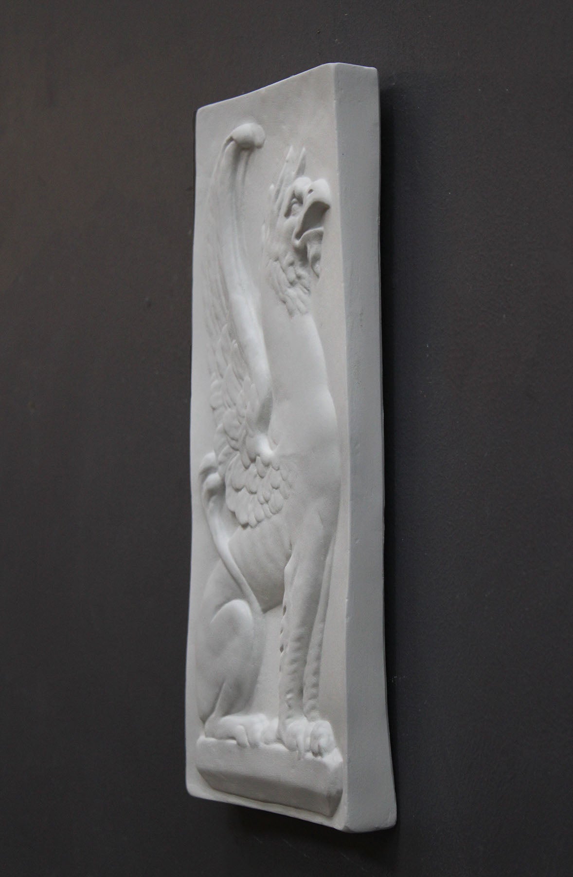 image of a plaster statue of a bust of griffin on a gray background