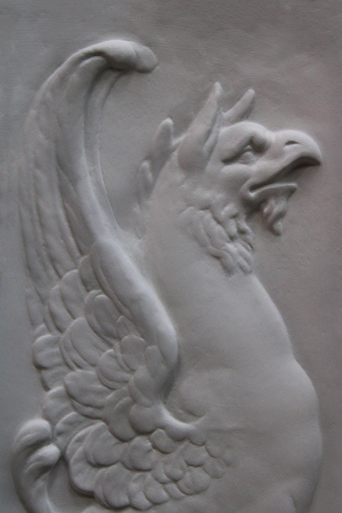 detailed image of a plaster statue of a bust of griffin on a gray background