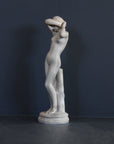 image of a plaster statue of a nude female figure, namely Phryne, on a gray background