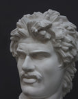 detail photo of white plaster cast bust of Gaul depicted with mustache and rope around neck atop white base on gray background