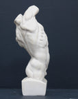 Photo of plaster cast sculpture of flayed male torso and a sculpting tool on a gray surface in front of a black background