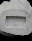 Photo of white plaster cast of a life cast of a clenched fisted hand on a black background, featuring the Caproni Collection stamp on the wrist