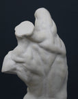Photo of plaster cast sculpture of flayed male torso and a sculpting tool on a gray surface in front of a black background
