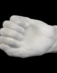 Photo of white plaster cast of a life cast of a clenched fisted hand on a black background