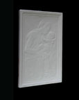 photo detail of plaster cast sculpture relief of the Madonna holding baby Jesus on her lap on black background