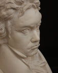 closeup photo of plaster cast sculpture of male bust of Ludwig van Beethoven in dress coat and ruffled necktie on black background