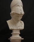 photo of plaster cast sculpture bust of female head, namely the goddess Minerva, with a helmet and looking down and placed on a pedestal with black background