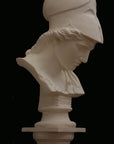 photo of plaster cast sculpture bust of female head, namely the goddess Minerva, with a helmet and looking down and placed on a pedestal with black background