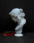 photo of plaster cast of sculpture bust of Ariadne or Bacchus with long, curly hair and head band next to books on a gray background