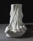 photo with gray background of plaster cast sculpture of flayed left foot on panel