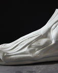 photo with gray background of plaster cast sculpture of flayed left foot on panel
