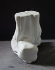 photo with gray background of plaster cast sculpture of flayed left foot on panel