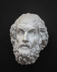 Photo of a white plaster cast mask from a sculpture of Homer on a black background