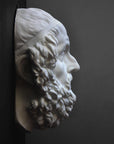 Photo of a white plaster cast of a mask of Homer on a black and gray background
