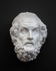 Photo of a white plaster cast mask from a sculpture of Homer on a black background