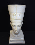 photo of plaster cast sculpture of bust of Nefertiti with crown and decorative collar on a decorative base with a black background