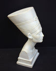 photo of plaster cast sculpture of bust of Nefertiti with crown and decorative collar on a decorative base with a black background